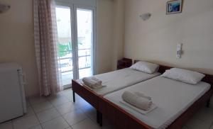 dwa łóżka w pokoju z oknem w obiekcie ΠΕΡΣΕΦΟΝΗ w mieście Kamena Wurla
