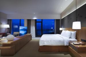 um quarto com uma cama, uma secretária e uma televisão em Crowne Plaza Nanchang Wanli, an IHG Hotel em Nanchang