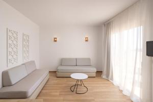 een witte woonkamer met een bank en een tafel bij Atlantica Akteon in Paphos City