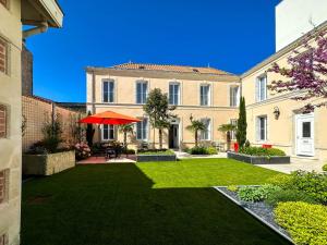 a courtyard with a lawn with a red umbrella at Nouvelle Vague in Fouras