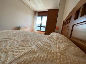 białe łóżko w pokoju z oknem w obiekcie Apartamento Salgueirón w mieście Cangas de Morrazo