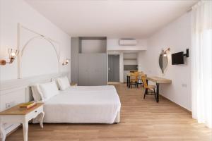 a bedroom with a white bed and a table at Atlantica Akteon in Paphos
