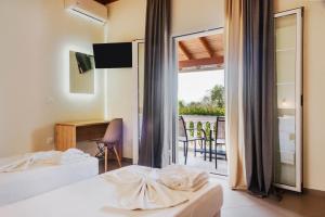 a bedroom with two beds and a desk and a balcony at Riposo Studios & Apartments in Kavos +92 photos