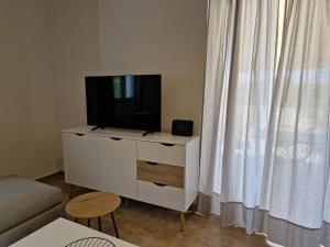 een woonkamer met een televisie op een wit dressoir bij MemRo Village House in Atsoupádhes