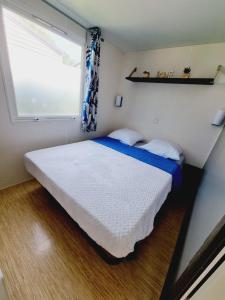 ein kleines Schlafzimmer mit einem Bett und einem Fenster in der Unterkunft Camping de l Orangerie de Lanniron Mobilhome Esprit Zen R26 in Quimper