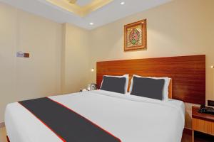una camera da letto con un grande letto bianco con testiera in legno di Hotel Pallava Rajadhani a Trivandrum