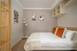 a bedroom with a bed with white sheets and orange pillows at Retro New Town Garden Flat in Edinburgh