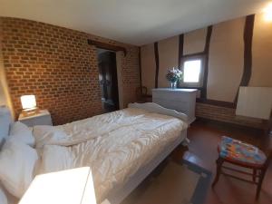 - une chambre avec un lit et un mur en briques dans l'établissement Les Hautes Charmante Ferme solognote, à Ligny-le-Ribault
