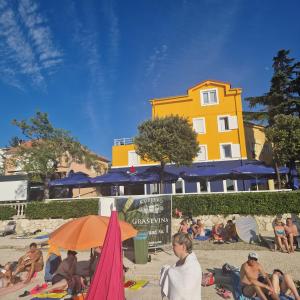 a group of people sitting on the beach at GRAND - Beachfront Rooms & Apartments in Selce