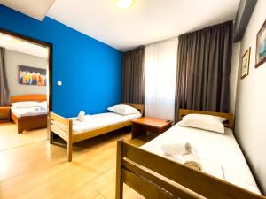 een kamer met 2 bedden en een blauwe muur bij GRAND - Premium rooms & apartments in Selce