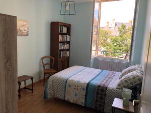 ein Schlafzimmer mit einem Bett, einem Bücherregal und einem Fenster in der Unterkunft Au pied du Marché in La Châtre
