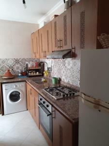 a kitchen with a stove and a white refrigerator at Appartement standing in Martil