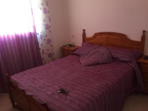 a bedroom with a large bed with a purple comforter at Appartement standing in Martil +5 photos