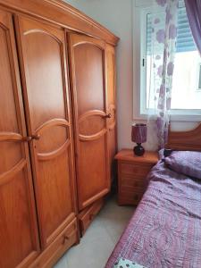 a bedroom with a large wooden cabinet next to a bed at Appartement standing in Martil