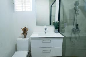 La salle de bains blanche est pourvue d'un lavabo et d'une douche. dans l'établissement Irofo City Apartments, à Accra