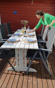 a woman sitting at a picnic table with chairs at Trygheim feriehus in Bud