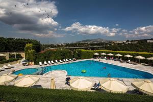 una gran piscina con sillas y sombrillas en Dekelia Hotel, en Atenas