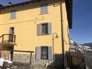 a yellow house with three windows and a fence at Ride Home - Val di Sole in Commezzadura