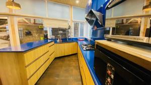 a large kitchen with blue counters and a stove at Clarence Cottage Mussoorie in Mussoorie