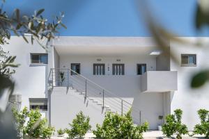 um edifício branco com escadas e árvores no primeiro plano em Diorisa House em Lardos