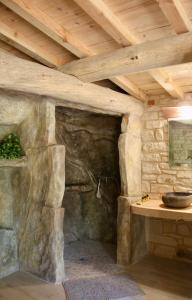 - une grotte en pierre avec un lavabo dans une chambre dotée d'un plafond en bois dans l'établissement Le doux refuge, à Gagnières