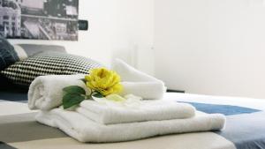 a pile of towels with a yellow flower on a bed at Sweet Roman Holiday in Fiumicino