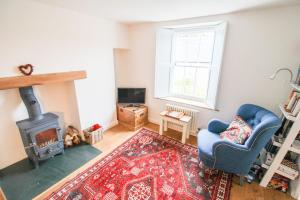 a living room with a blue chair and a wood stove at Sedbergh Cottage, Sedbergh in Sedbergh
