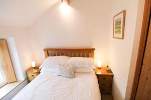 a bedroom with a bed with white sheets and two candles at Sedbergh Cottage, Sedbergh in Sedbergh