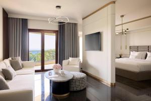 um quarto de hotel com um sofá, uma cama e uma mesa em Pomegranate Wellness Spa Hotel em Nea Potidaea
