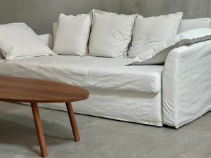 Sofá blanco con almohadas blancas y mesa de madera en Loft studio in Pagrati en Atenas