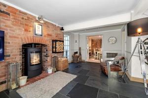 a living room with a brick wall and a fireplace at Stunning Country 4 bedroom Cottage for weekly or monthly stays in Honiley