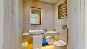 a bathroom with a sink and a toilet and a mirror at Acrotel Elea Beach in Elia