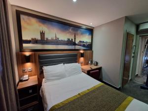 a hotel room with a bed and a painting on the wall at London Court Hotel in London