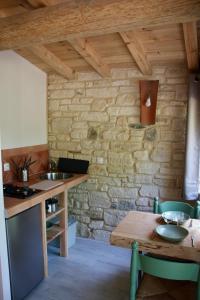 - une cuisine avec une table et un mur en pierre dans l'établissement Le doux refuge, à Gagnières