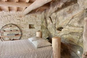 - une chambre avec un lit et un mur en pierre dans l'établissement Le doux refuge, à Gagnières