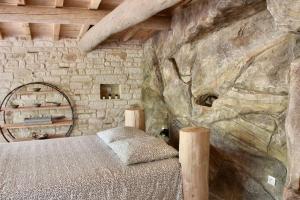 a bedroom with a bed and a rock wall at Le doux refuge in Gagnières