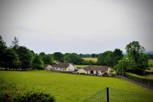 a large green field with houses and a fence at Crebilly Cottage - Rural Life doesn't get better in Ballymena