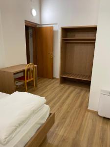 a bedroom with a bed and a table and a closet at Rifugio Pian dei Ciclamini in Lusevera