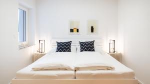 a white bedroom with a large white bed with two lamps at Apartments Jesse in Sankt Kanzian