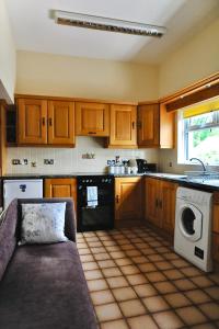 a kitchen with wooden cabinets and a couch in it at Crebilly Cottage - Rural Life doesn't get better in Ballymena