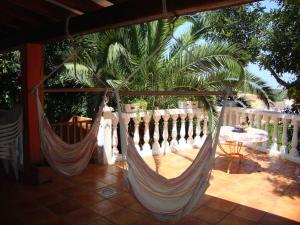 2 Hängematten auf einer Veranda mit einem Tisch und einem Zaun in der Unterkunft Villa climatisée, piscine in Jeresa