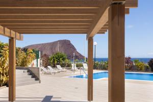 einen Blick auf den Pool im Resort mit einem Berg im Hintergrund in der Unterkunft Home2Book Stylish & Relax Attic La Tejita, Pool in La Tejita