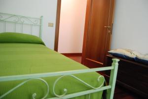 Monte San VitoにあるLa Collina Sul Mare B&Bのベッドルーム1室(緑のベッド1台、木製キャビネット付)