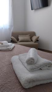 1 cama con toallas blancas y sofá en B&B Civico 137 en Taurianova