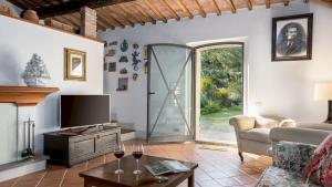 een woonkamer met een televisie en wijnglazen op een tafel bij MULINO NEL CHIANTI 10, Emma Villas in Gaiole in Chianti