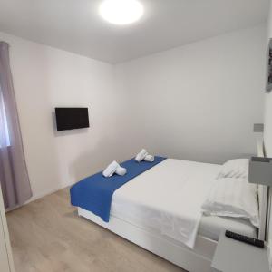 a white bedroom with a bed with two towels on it at Apartments Anamarija in Zadar