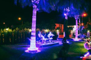 dos personas sentadas en un banco bajo palmeras por la noche en Edem Flower Hotel, en Kemer