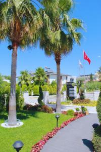 a walkway through a park with palm trees and flowers at Edem Flower Hotel in Kemer