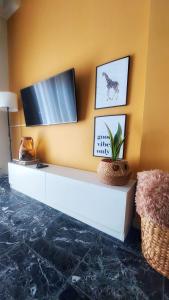 un soggiorno con TV su una parete gialla di Cosy Retro Apartment a Città di Zante