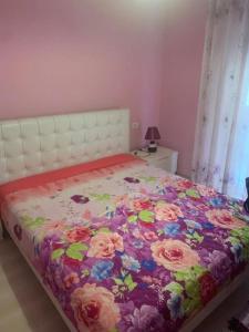 1 dormitorio con 1 cama con colcha de flores en Very nice and romantic apartment, en Pogradec